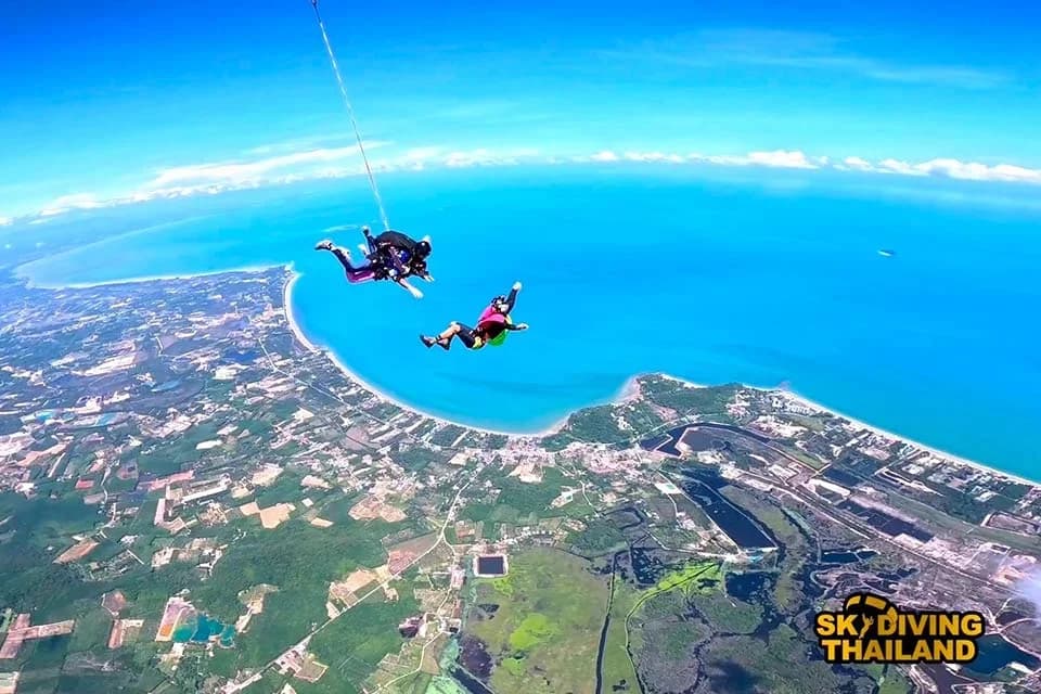 라용 해안 상공에서 강사와 함께 탠덤 점프하는 Skydiving Thailand 공식 사진